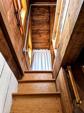 Eine Holztreppe mit einem weißen Vorhang oben.