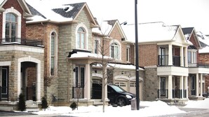 A row of residential buildings with stone facades, large windows, and balconies.