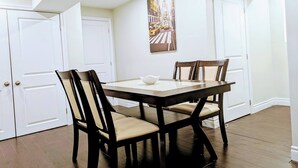 A dining area with a table and chairs, white doors, and a painting on the wall.