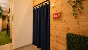 A wooden wall with a sign indicating room numbers 13-22, a blue curtain, and a green plant. - Nusantara Tajur Bogor Hostel By Reccoma (Bogor)