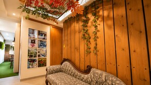 A room with a wooden wall, a sofa, and a ceiling with a grid-like structure. - Nusantara Tajur Bogor Hostel By Reccoma (Bogor)