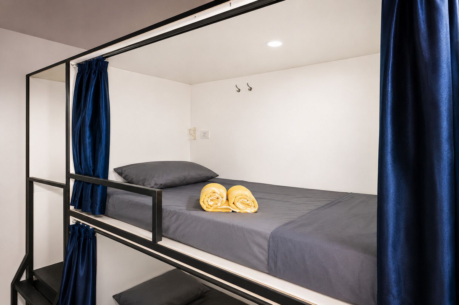 A bunk bed with a mirror, a pillow, and rolled towels.