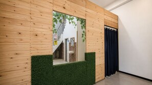 A wooden wall with a mirror, a green wall-mounted planter, and a door with a dark curtain.
