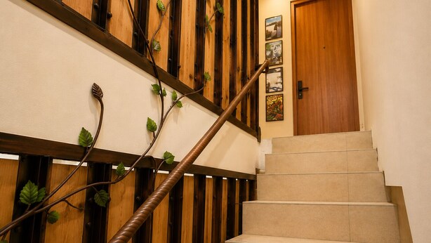 A staircase with wooden railings and a handrail, leading to a door with a picture frame on the wall. - Nusantara Tajur Bogor Hostel By Reccoma (Bogor)