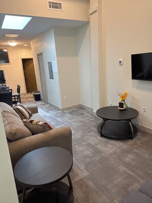 A modern living room with a sofa, two round tables, a TV, and a small decorative plant. - Hilliard Lofts (Cleveland)