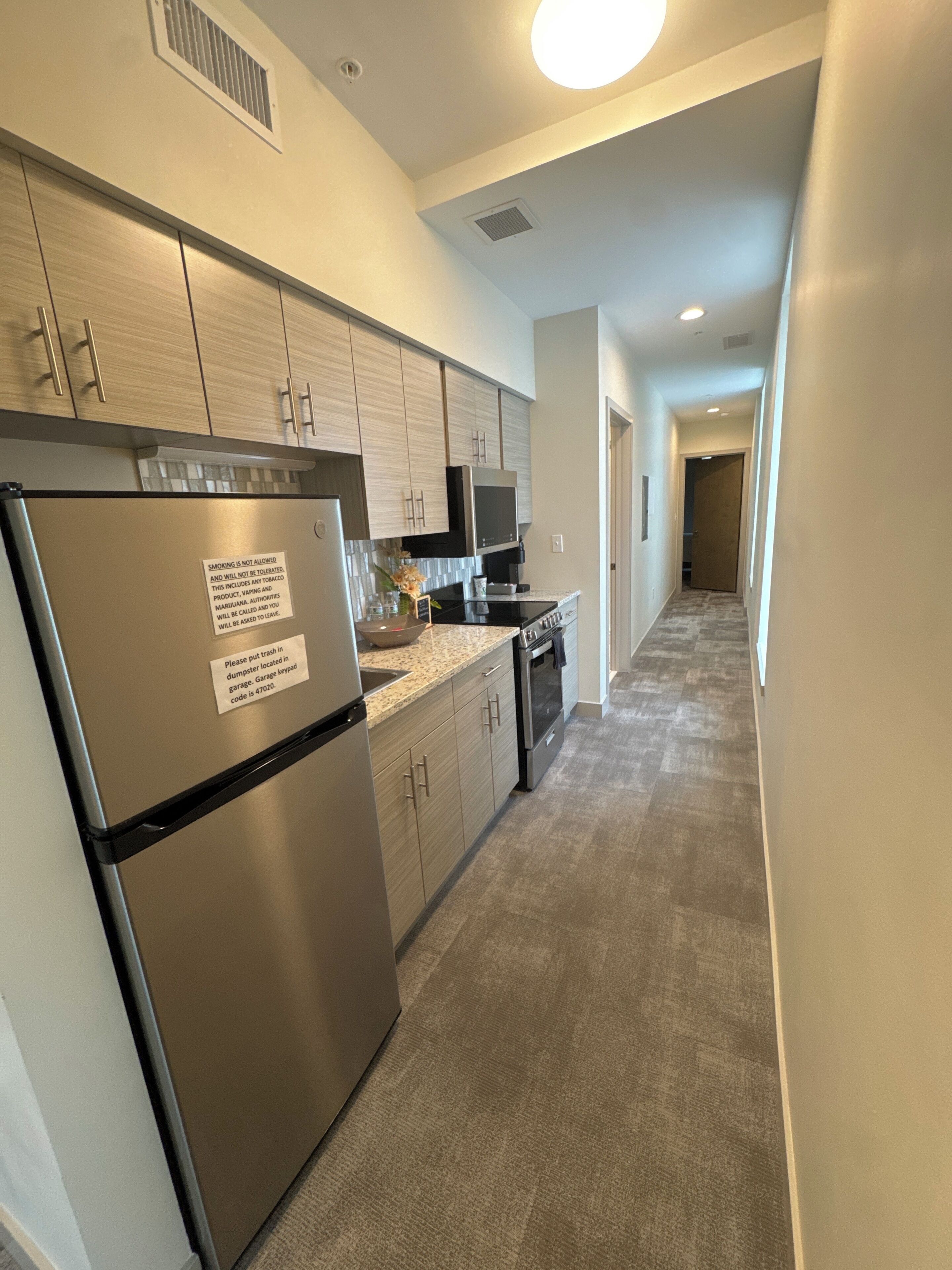 A modern kitchen with stainless steel appliances, wooden cabinets, and a granite countertop.