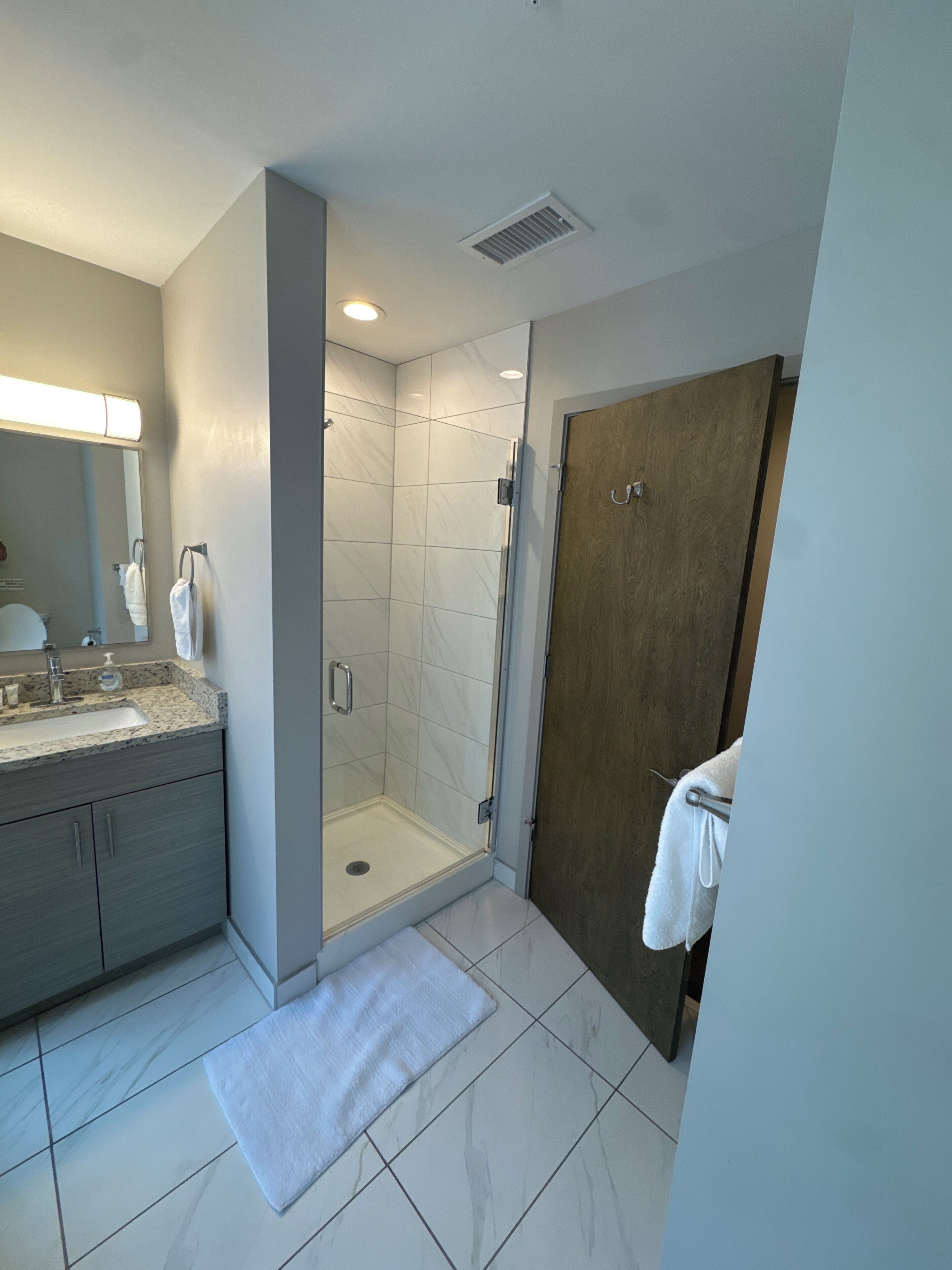 A modern bathroom with a shower, sink, and mirror.