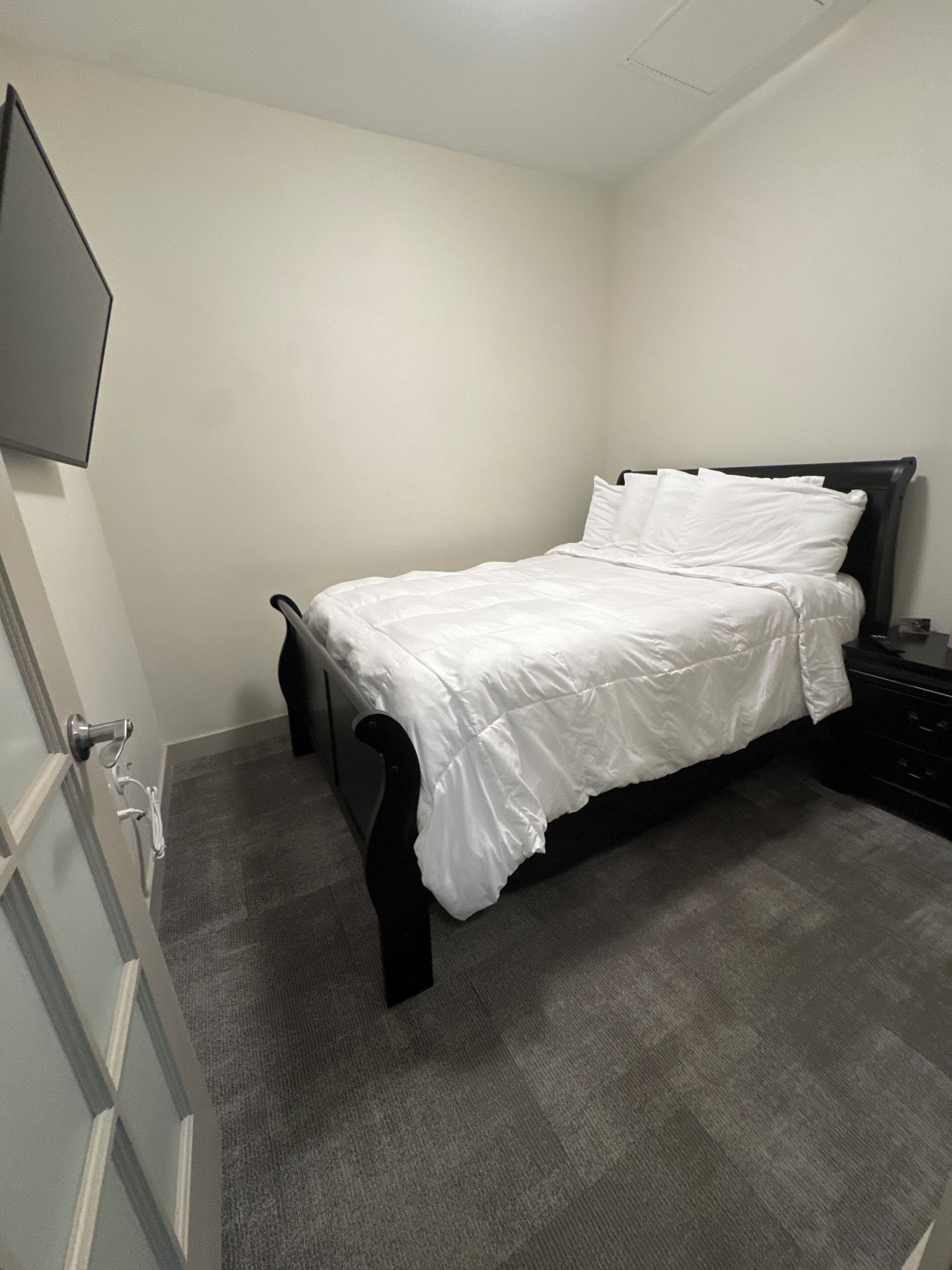 Een slaapkamer met een bed, een ladekast en een deur.