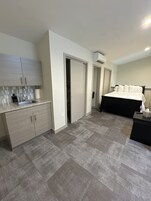A bedroom with a bed, a bathroom with a sink and mirror, and a closet.