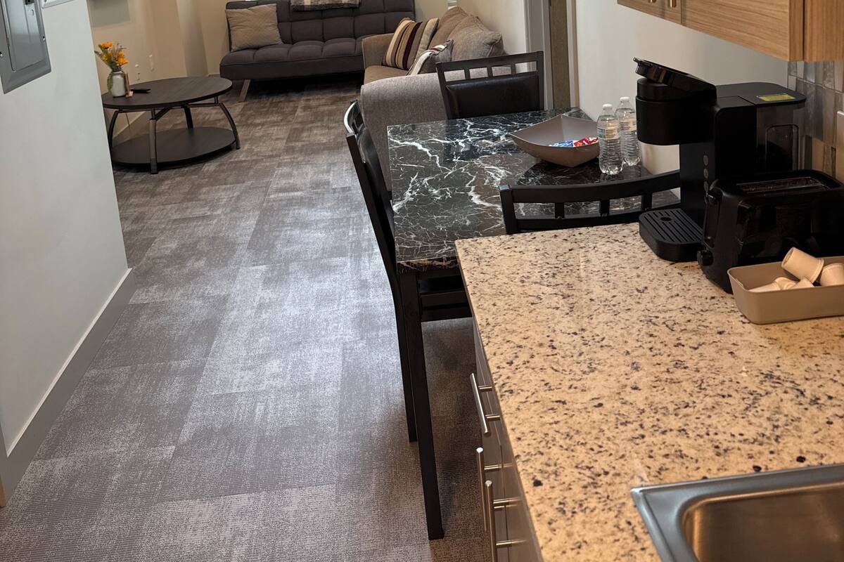 A modern kitchen with a marble countertop, a coffee machine, and a sink.