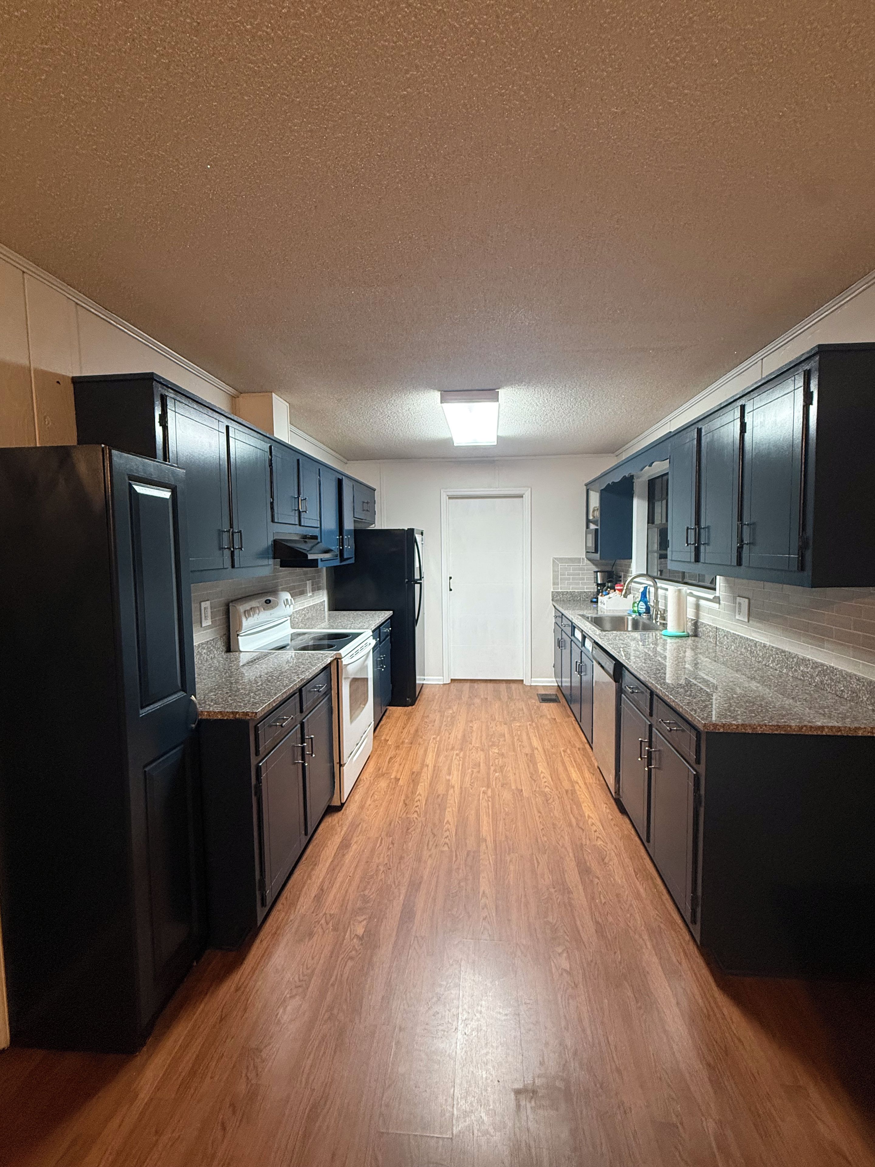 Una cocina con armarios oscuros, un refrigerador y un lavavajillas.