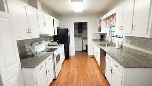 A kitchen with white cabinets, a black refrigerator, a stove, and a microwave. - Peaceful country home minutes from Lake Mitchell (Clanton)