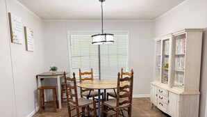 A dining area with a round table, wooden chairs, a small side table, a cabinet with drawers, and a ceiling fan. - Peaceful country home minutes from Lake Mitchell (Clanton)