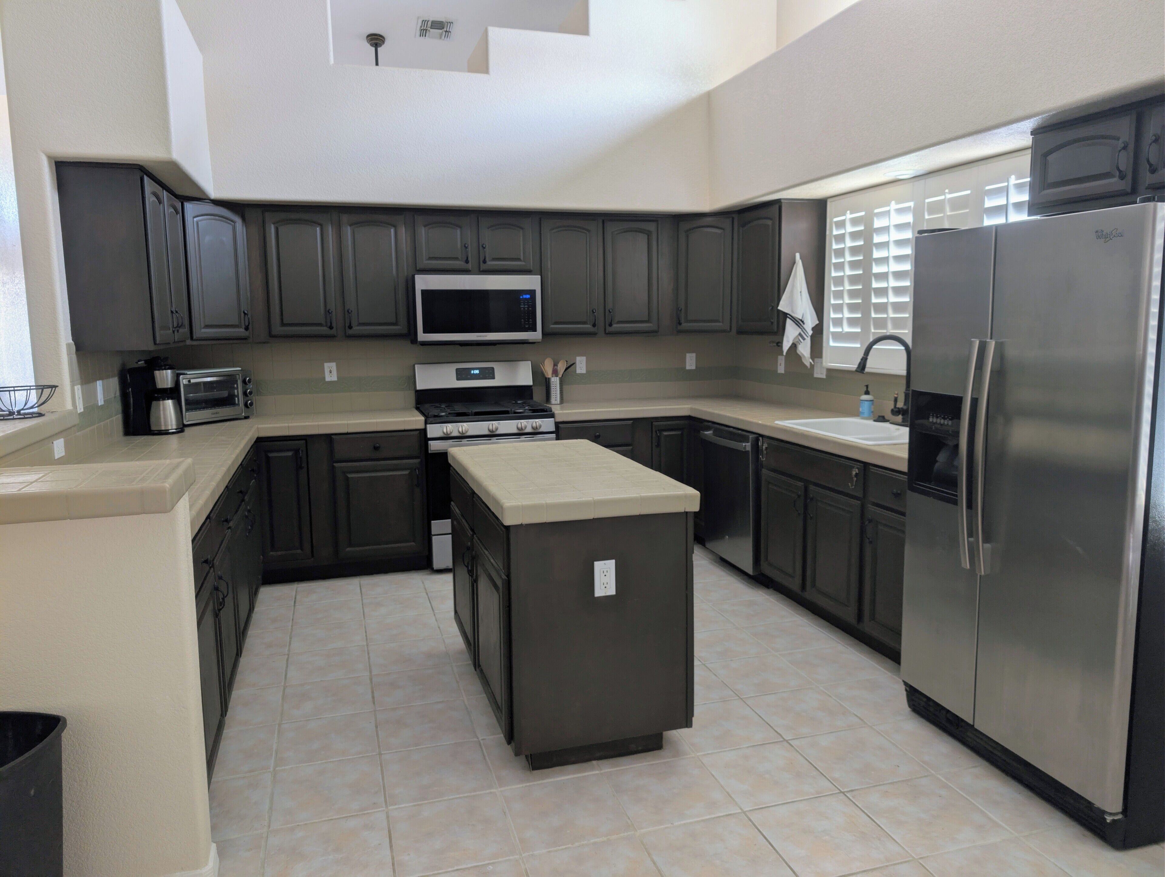 A modern kitchen with dark cabinets, a microwave, a stove, and a refrigerator.