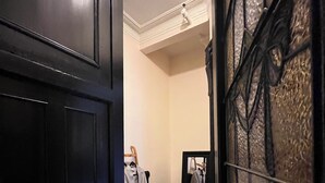 A room with a wooden door, a mirror, a small table with a pink towel, and a robe hanging on a rack. - Peaceful 1-bedroom suite in boutique guesthouse with AC in vibrant New York (New York)