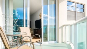 En balkong med ett glasbord och stolar, en tv och utsikt över staden.