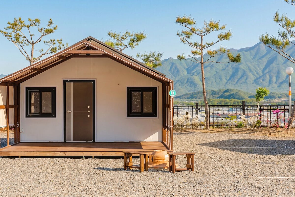 A small wooden cabin with a front door, two windows, and a porch.