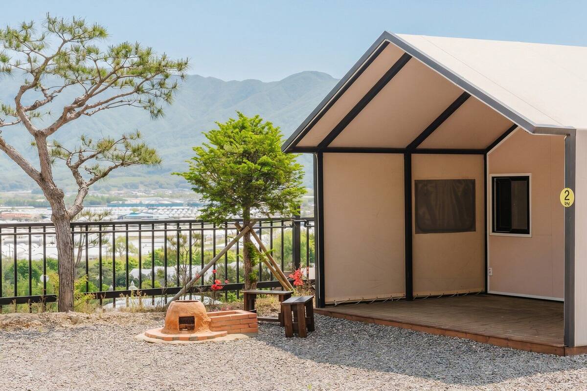 A small, single-room cabin with a view of mountains and a body of water.