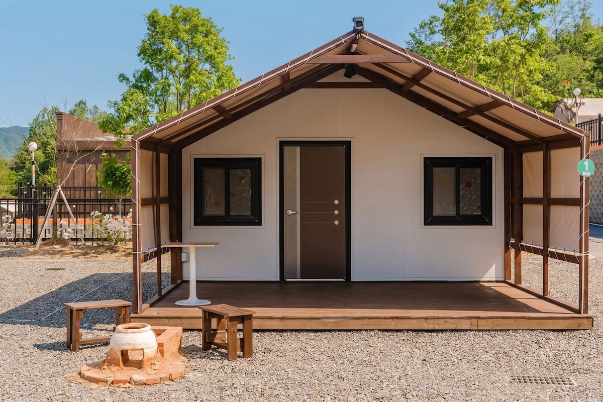 A small, single-room cabin with a wooden deck, a door, and two windows.