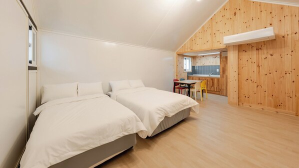 A bedroom with two beds, a small kitchen area, and a dining table with chairs. - Pocheon Youngyoung Glamping (Pocheon)