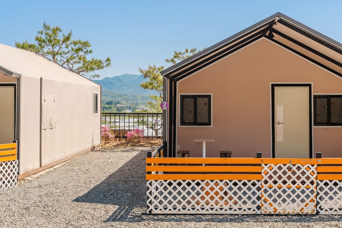 A small, single-room cabin with a door, windows, and a bench outside.