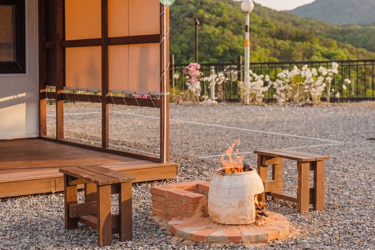 A wooden deck with a fire pit, benches, and a view of a mountainous landscape.