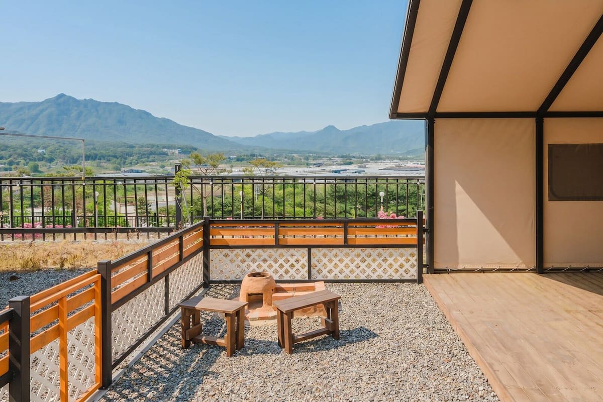 A balcony with a wooden bench, a table, and a view of mountains.
