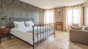 A bedroom with a four-poster bed, a wooden nightstand, a wooden chair, a small table, and a sofa. - Château avec piscine privée (Valréas)