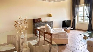A living room with a glass coffee table, a sofa, a TV, and a fireplace. - Château avec piscine privée (Valréas)