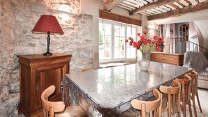 A dining area with a marble table, wooden chairs, a red lamp, and a vase with red flowers. - Maison avec piscine privée (Mazan)