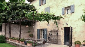 A courtyard with a table and chairs, potted plants, and a pergola. - Maison avec piscine privée (Mazan)