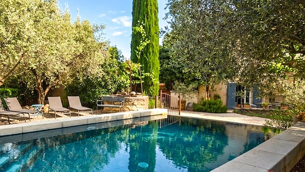A swimming pool with lounge chairs and a stone wall. - Maison avec piscine privée (Mazan)
