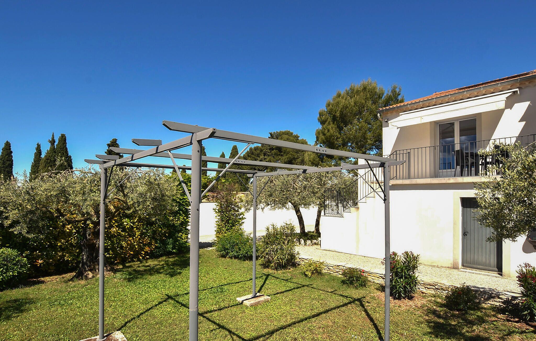 Ein Wohnhaus im modernen Architekturstil, mit einem gepflegten Garten und einer Metall-Pergola.