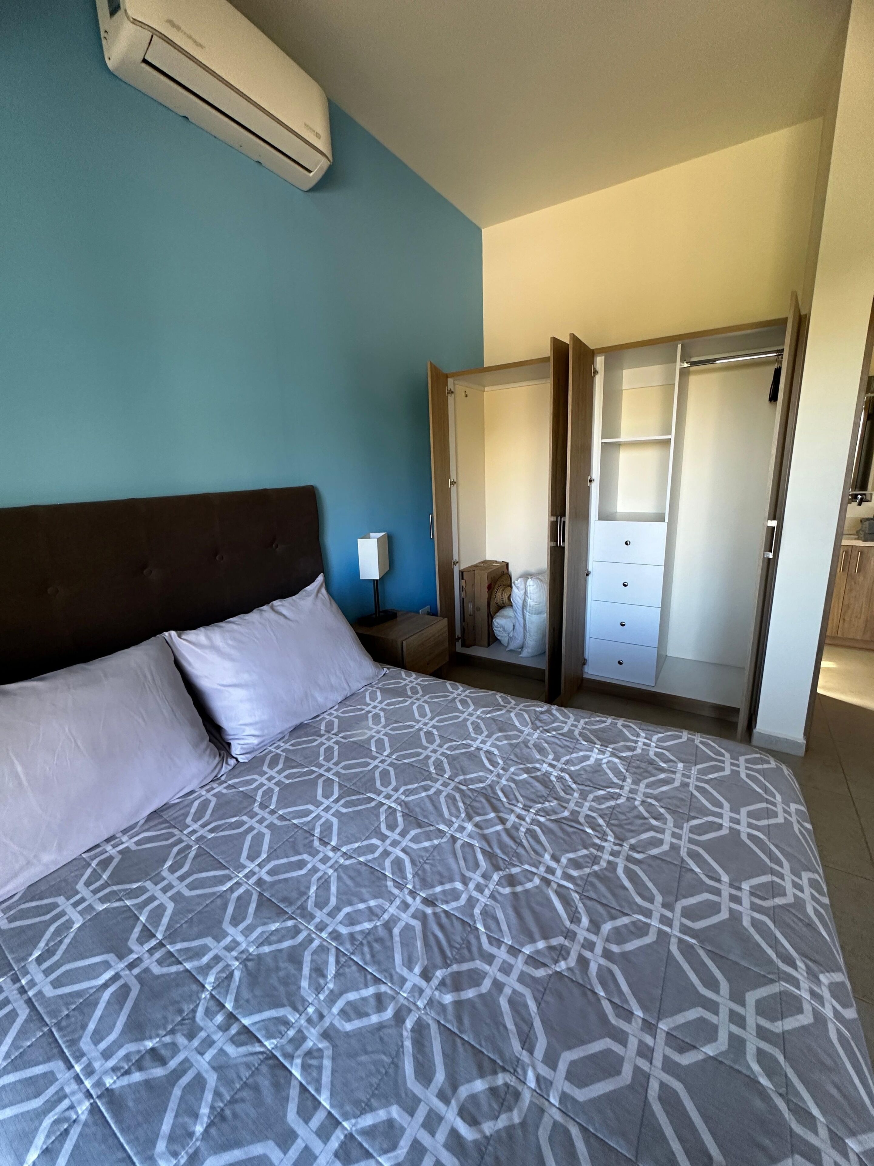 Une chambre avec un grand lit, un appareil de climatisation, une armoire et une table de chevet.