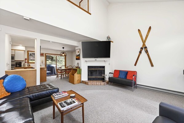 Una sala de estar con chimenea, televisor, sofá y mesa de centro.