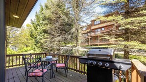 Eine Terrasse mit Grill, Stühlen und Blick auf eine Hütte.
