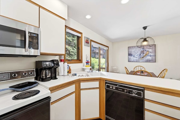 A modern kitchen with a microwave, stove, coffee maker, and dishwasher.