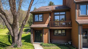 Ein zweistöckiges Holzhaus mit Veranda, Garage und kleiner Terrasse.