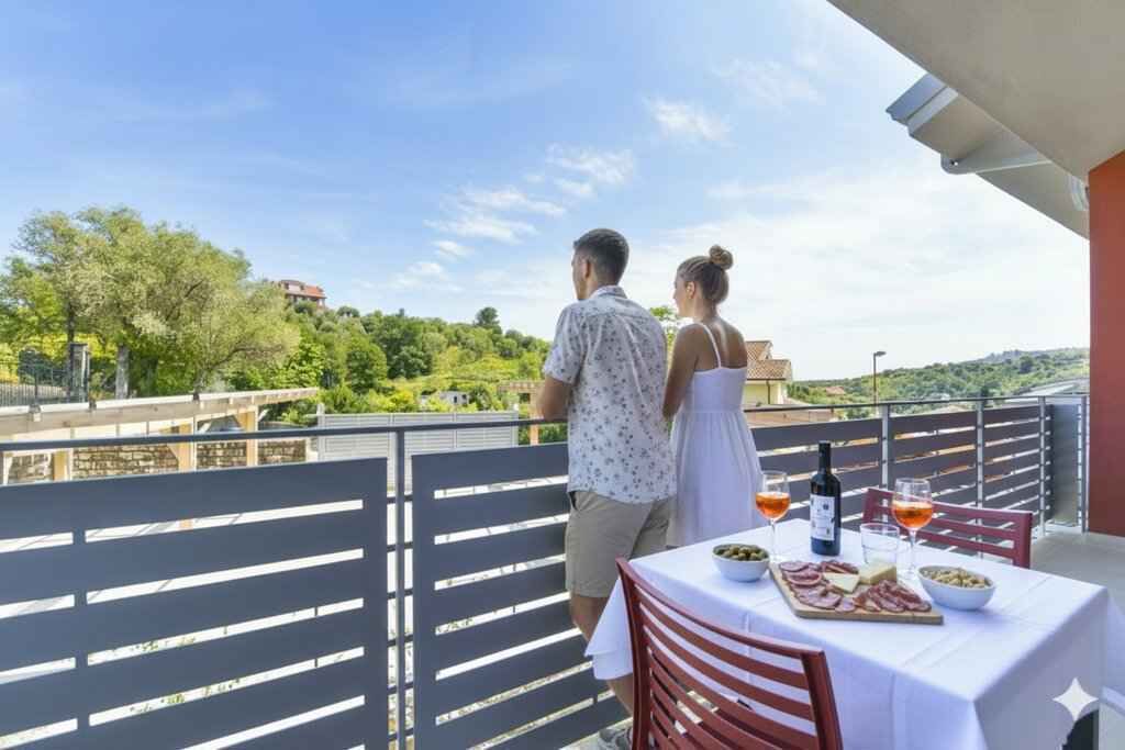 Et par nyder en storslået udsigt fra en balkon med et bord dækket til et måltid.