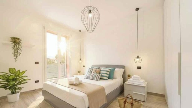 Un dormitorio moderno con una cama, mesitas de noche, una lámpara colgante y una planta en maceta.
