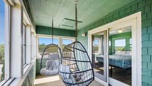 Een kamer met een hangstoel, een bed en uitzicht op de omgeving.