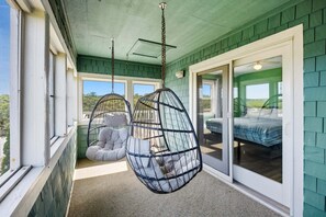 Ein Zimmer mit Hängesessel, Bett und Blick ins Freie.