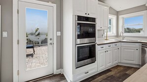 Een keuken met witte kastjes, een dubbele oven en een raam met uitzicht.