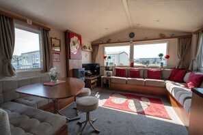 Ein gemütliches Wohnmobil-Interieur mit Esstisch, Sofa und Fernseher.