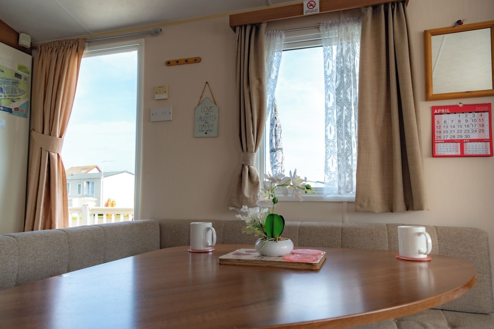 A cozy room with a wooden table, a potted plant, and a calendar on the wall.