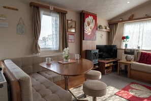 Ein gemütliches Wohnzimmer mit einer Couch, einem kleinen Tisch, einem Fernseher und einem Kamin.
