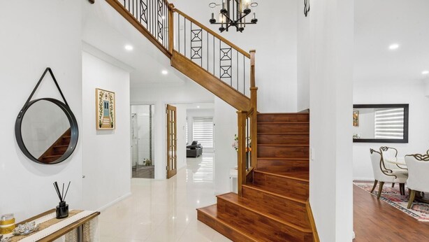 Een modern interieur met een houten trap, een ronde spiegel en een eetgedeelte met stoelen.