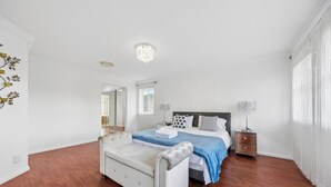 Een slaapkamer met een bed, nachtkastjes, een stoel, een spiegel en een kroonluchter.