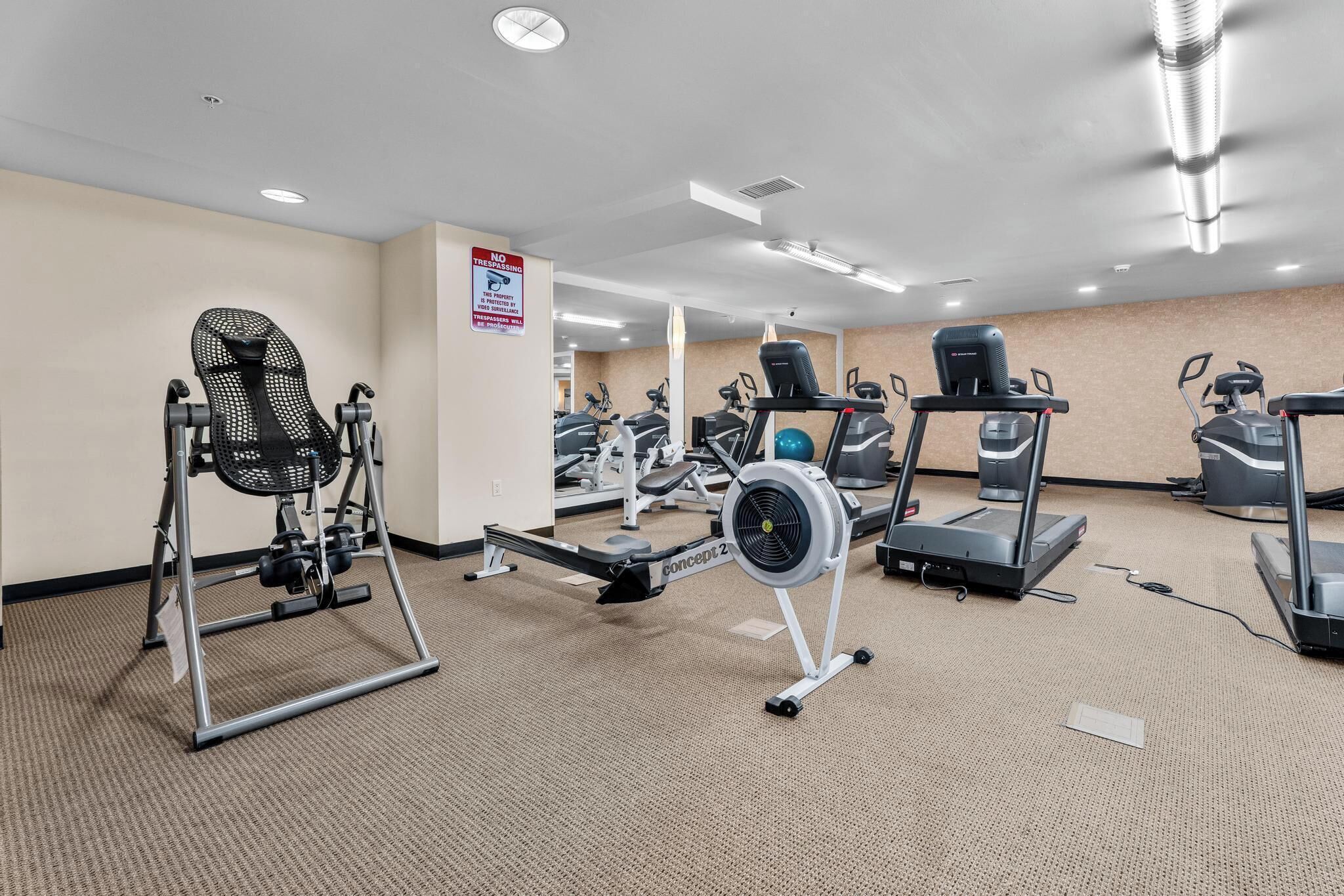 A gym with various exercise equipment, including treadmills and a rowing machine.