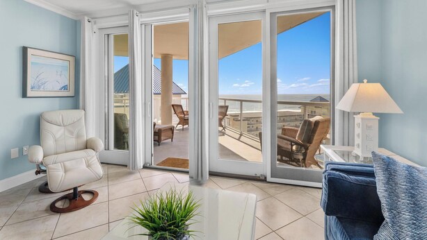 Ein Zimmer mit einer großen Glasschiebetür, die auf einen Balkon mit Gartenmöbeln führt.